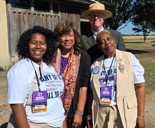 Three partners stand with a park ranger