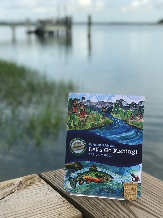 a jr ranger booklet on fishing with water and a dock in the background