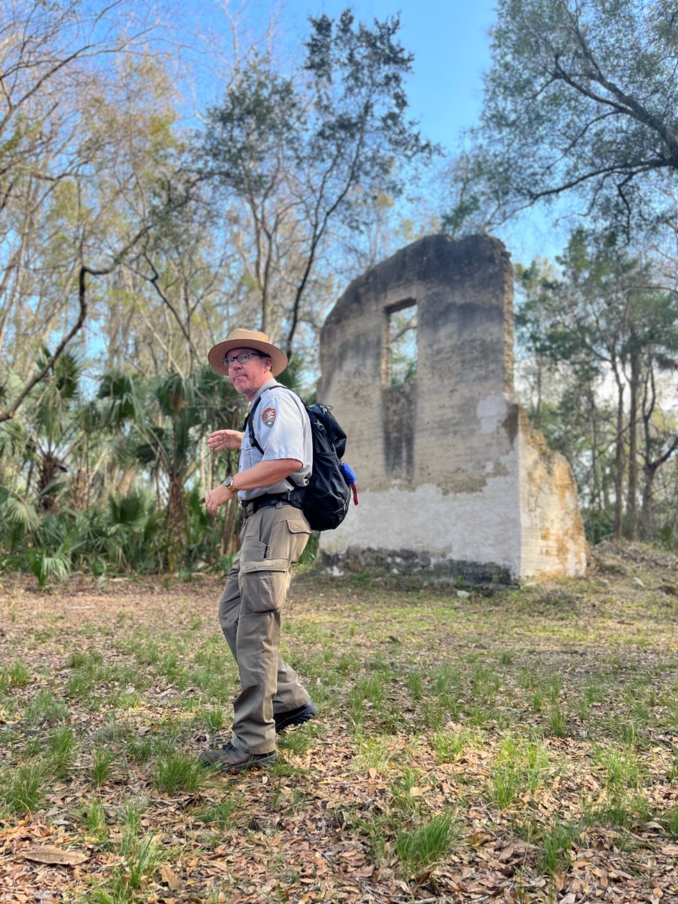ranger stands with palntation ruins in forest