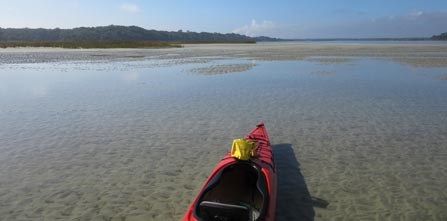 red kayak at low tide shallow waters surround