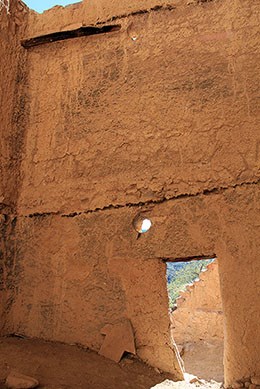 Upper Cliff Dwelling Room 5. Wall with a door and small hole in the bottom half. A line runs across the wall above the hole showing where the ceiling would have been located.