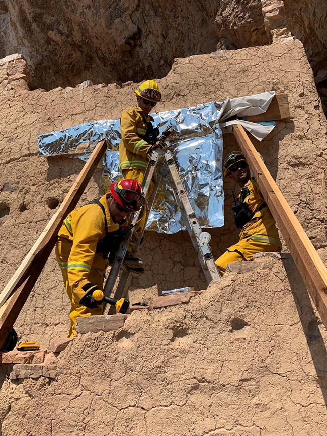 Crew wrapping modern wood in cliff dwelling
