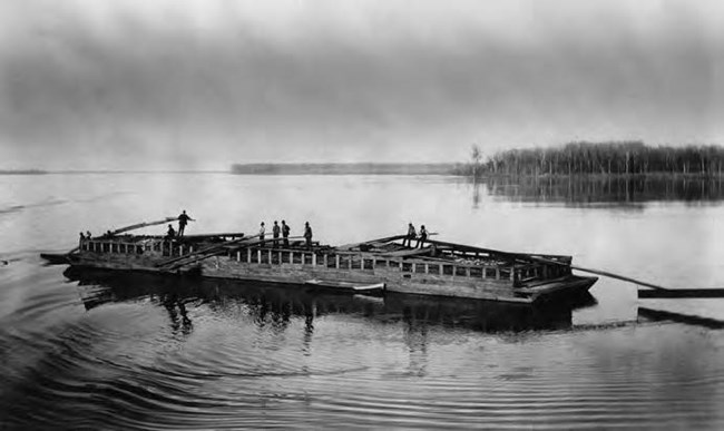 An illustration of a flatboat on the river with men on deck.