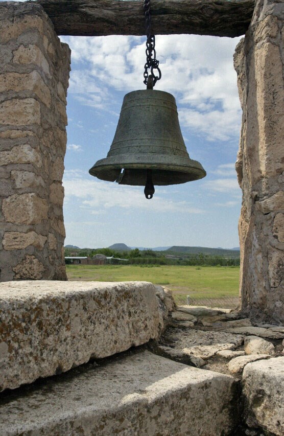 bell in stone tower with landscape behind