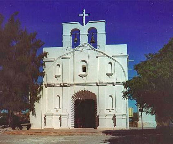 color photo of modern white-washed church with niches and cross at top
