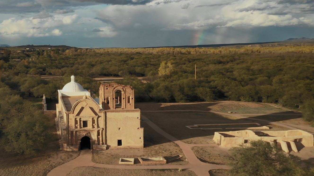 aerial shot of church with clouds and rainbow in the distance