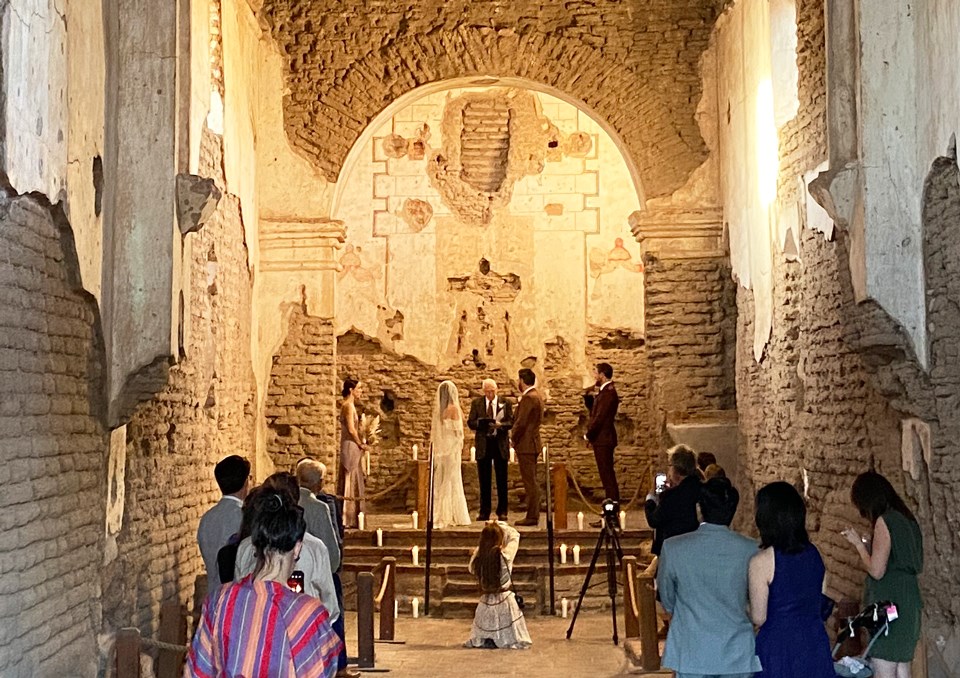 bride and groom inside golden-lit church, with small group of family in attendance