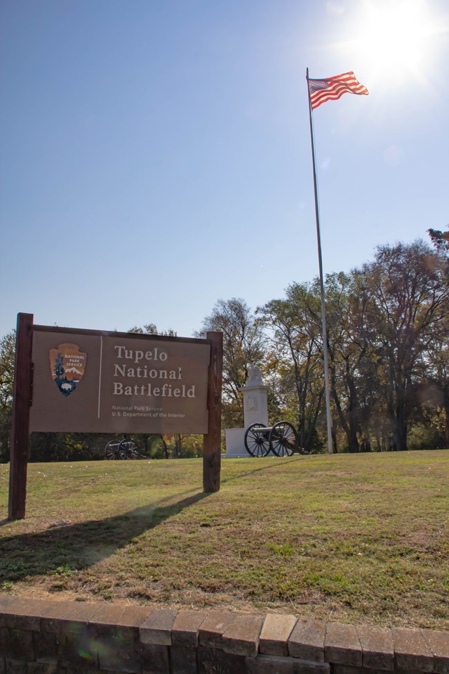 The National Park Service sign for Tupelo National Battlefield with the American flag flying tall