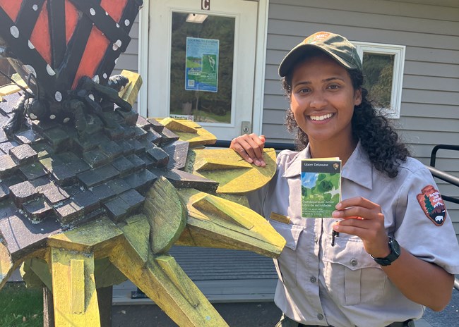 Latina park ranger holding the Upper Delaware Junior Ranger book and smiling