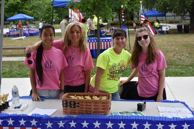 Volunteers stand behind an activity table at the July 4th Community Picnic.