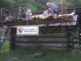 volunteers repair the shingle roof on a hut