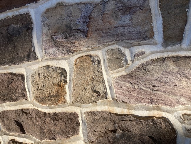 Rock wall with rocks of different colors and light gray mortar