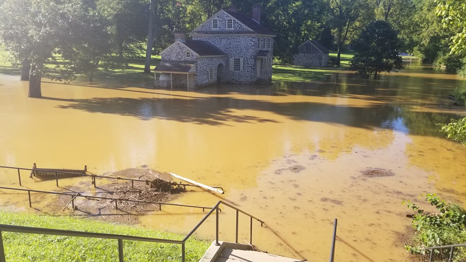 A two story stone house surrounded by flood waters.