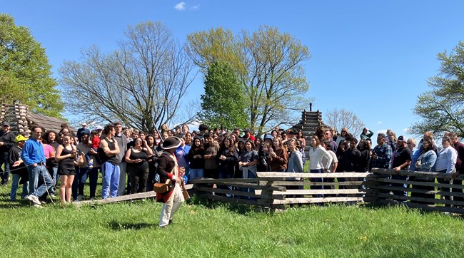 A crowd of people gathered along a wooden split-rail fence