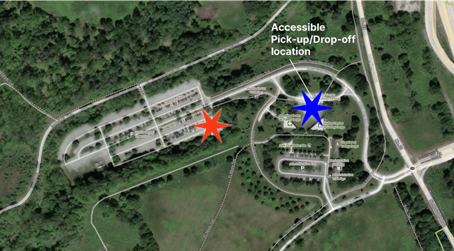 Aerial satellite image of the parking lot and visitor center area at valley forge with a red star near the restroom marking pick-up/drop-off location and blue star marking accessible pick-up/drop-off location.