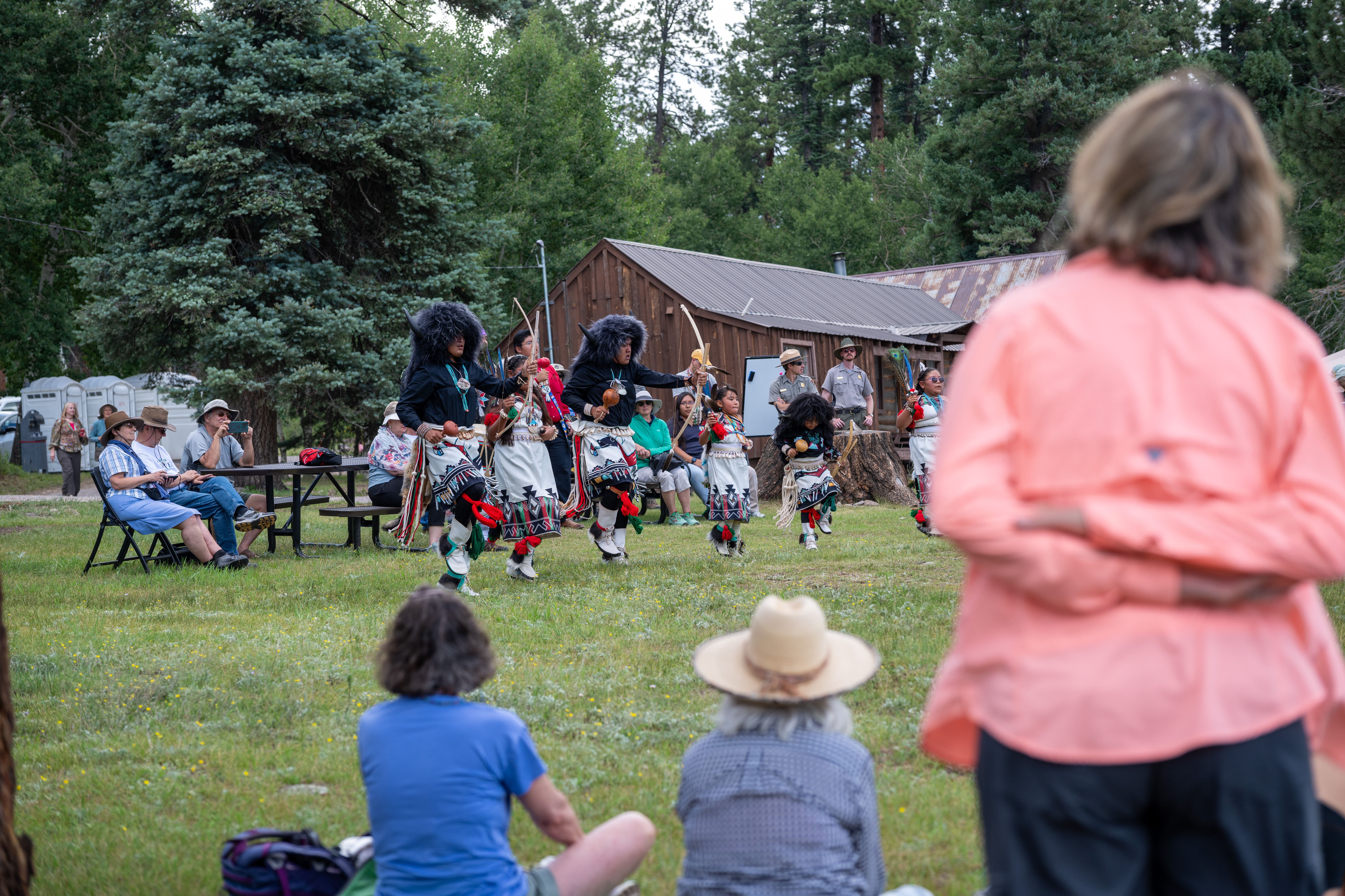 A pueblo dance group performs outdoors for an audience
