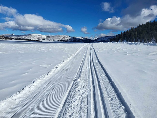 A groomed ski trail through a snowy valley.