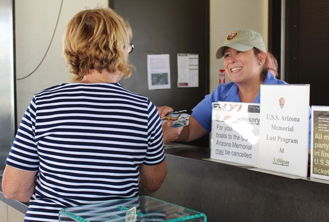 Volunteer Ann Marie assists a visitor at the Pearl Harbor Visitor Center ticket counter.