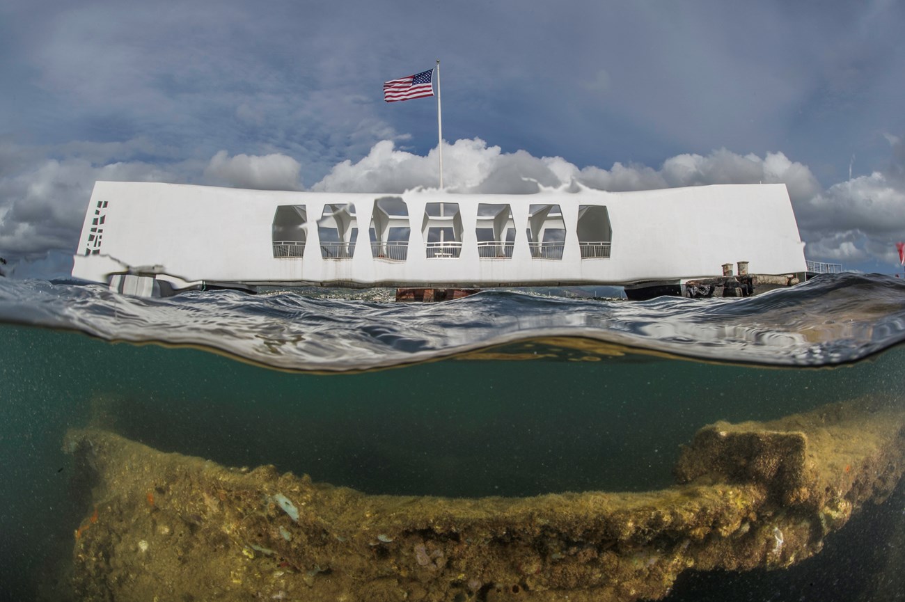 A view of the USS Arizona Memorial that also shows the wreckage of the USS Arizona under the waters of Pearl Harbor.
