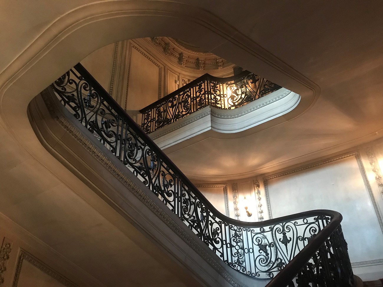 A stone staircase with decorative bronze railing rising three flights.