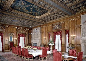 A large paneled room with massive stone fireplaces and a large dining table.