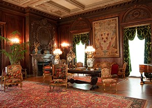 A large room with gilt chairs, rich carpets, and tapestries on the walls.
