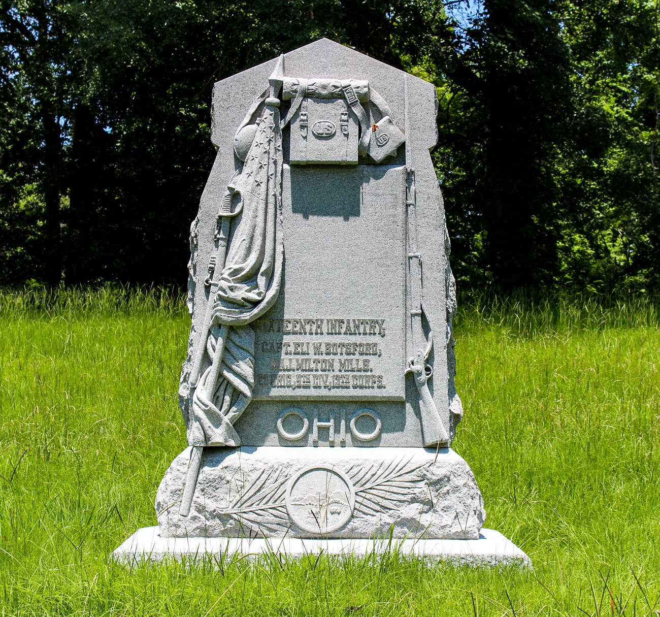 A stone monument with a military bag and supplies carved into it. Ohio carved largely on the top of the monument
