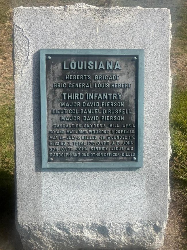 Large white stone marker with metal plaque