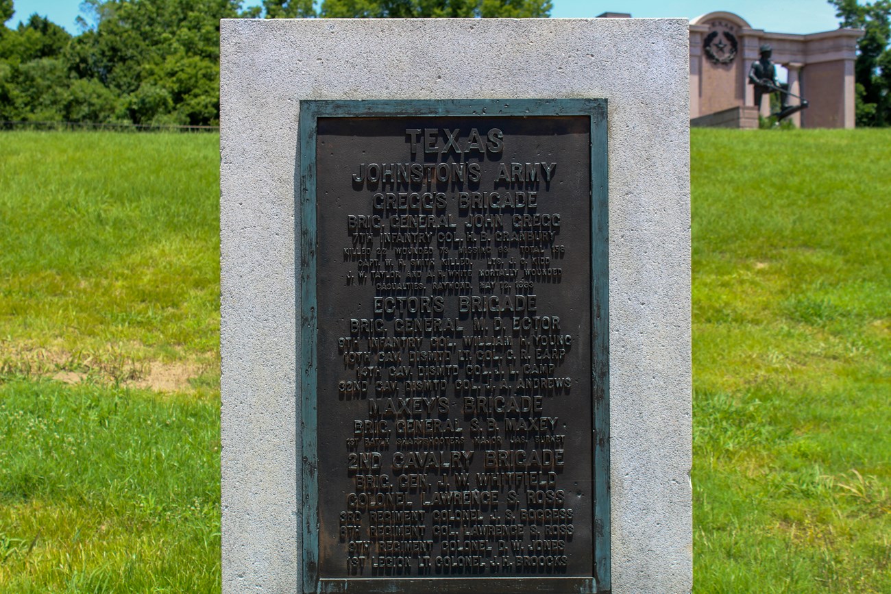 A bronze tablet monument for 7th Texas Infantry with the Texas State memorial in the background