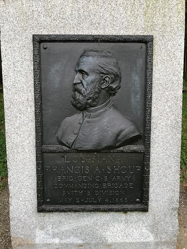 A bronze bas relief side portrait of man with full beard.