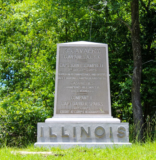 A regimental marker made of granite with a short inscription. At the bottom of the marker is Illinois is larger font