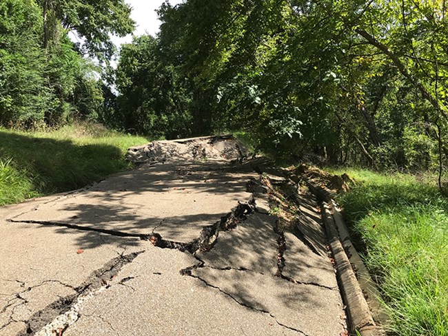 Road with damage including large crack and sections of the road dropped a few feet