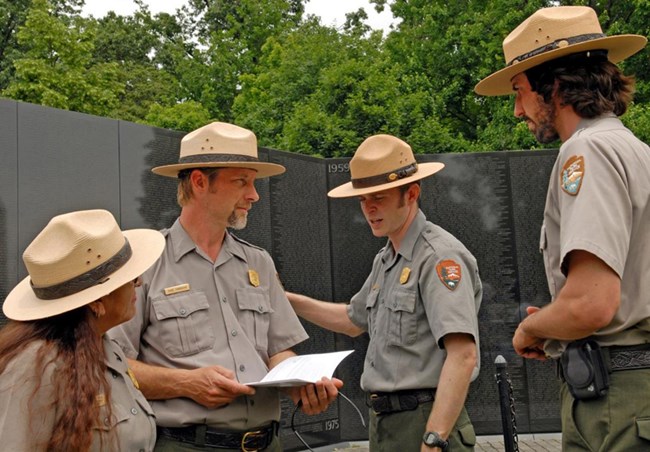 Four rangers have a discussion in front of the Vietnam Wall