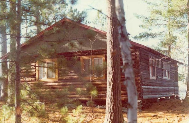 A historic log cabin surrounded by pine trees.