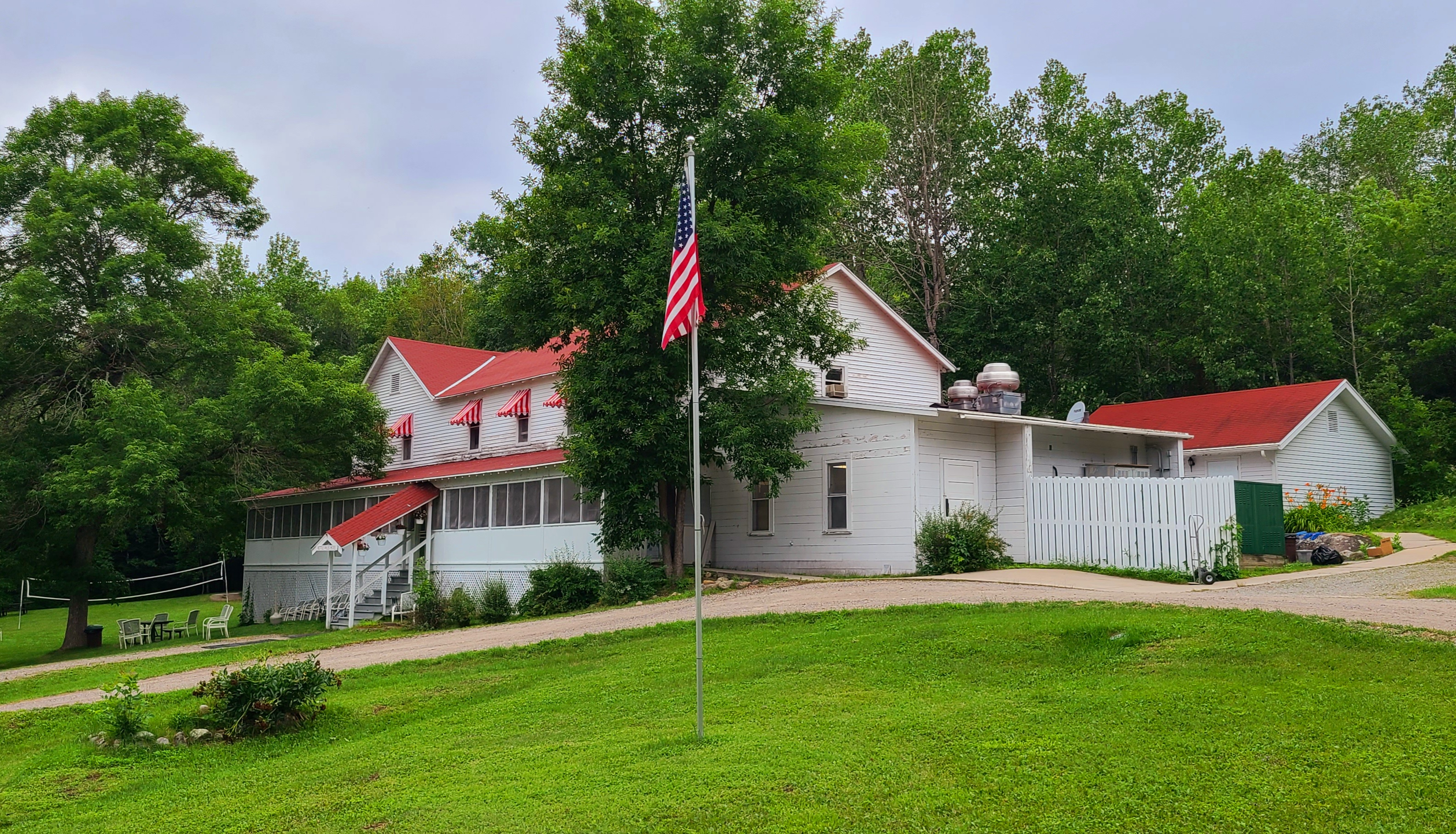 Red and white colored historic Kettle Falls Hotel surrounded by lush greenery in the springtime.