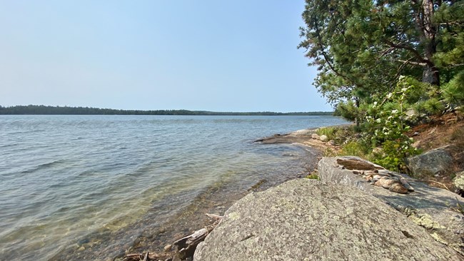 A scenic lake reflects the blue sky and trees of its shoreline