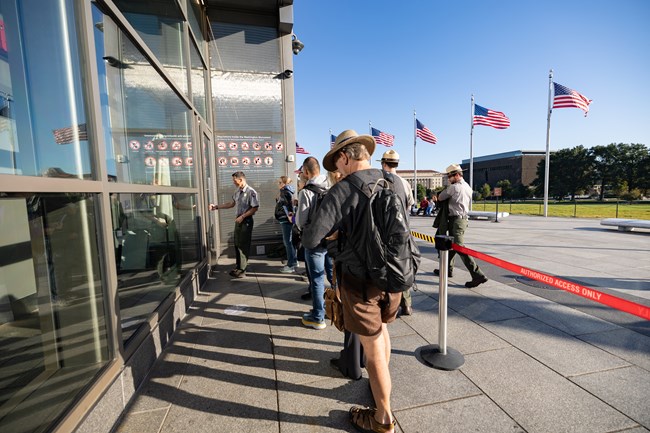 Visitors wait in line to enter the Washington Monument contained by queue line ropes.