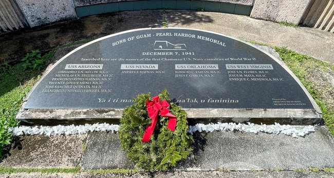 Semicircular plaque on the ground with the names of the twelve CHamoru men who died during the attack on Pearl Harbor