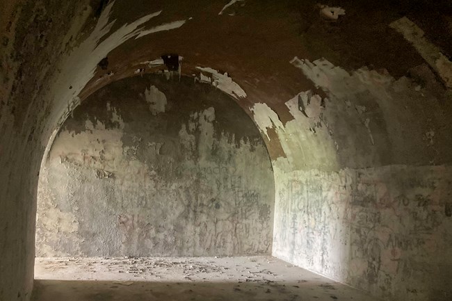A U-shaped concrete tunnel with light streaming in from one end.