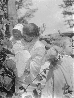 A black and white photo of a women with two children.