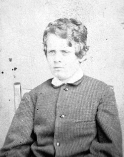 A black and white photo of a young boy sitting.