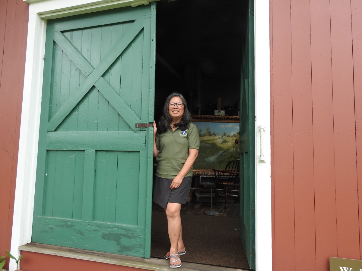 Weir Farm Tour Guide standing in doorway of the Weir Studio - the door is a deep green and the studio a vibrant red