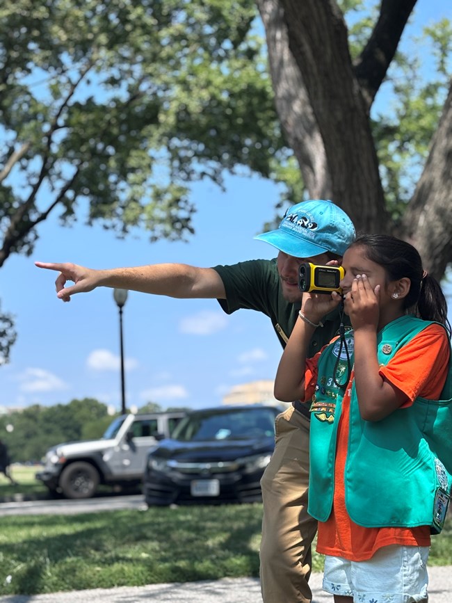 Volunteer showing a Girl Scout how to use a tree measuring tool