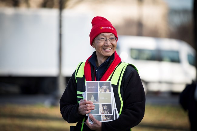 Volunteer holding National Christmas Tree Lighting booklets