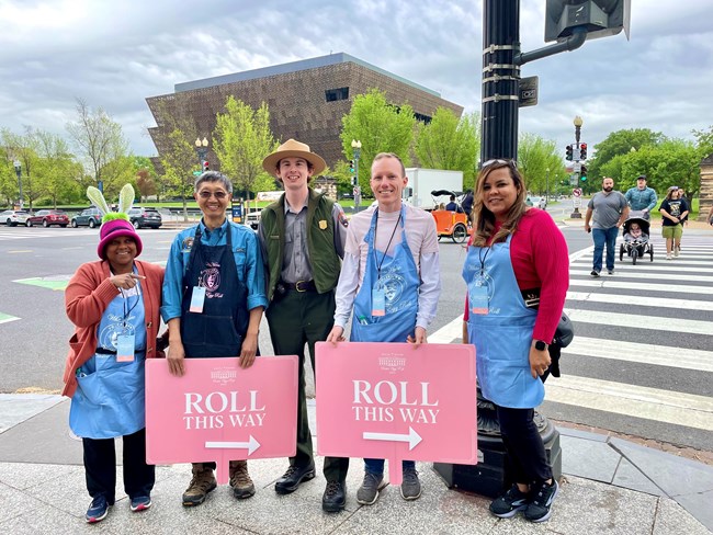 Group of volunteers with signs saying "Roll This Way"