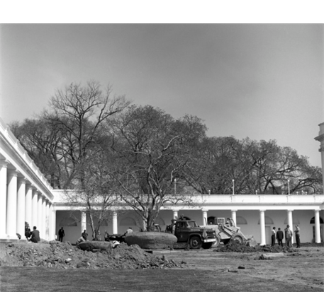 Black and white photo of the Rose Garden under construction. Workers and vehicles and piles of dirt are spread out across the unfinished Rose Garden.