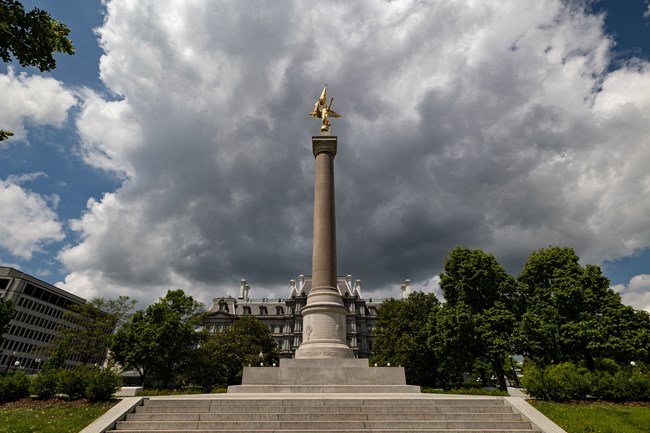 A golden, winged figure tops a tall marble column.