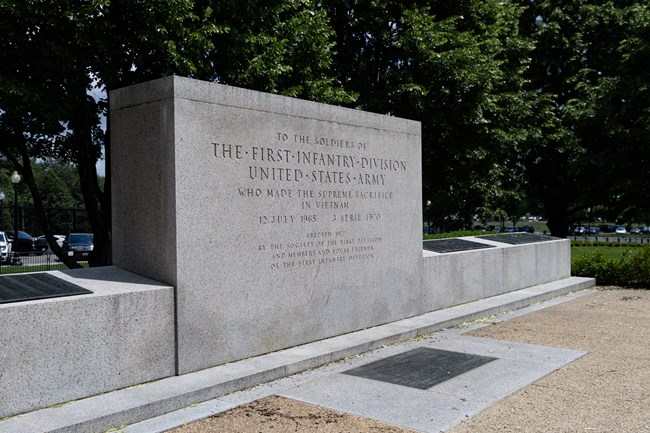 A large, rectangular monument with a low, angled wall with bronze plaques on it.