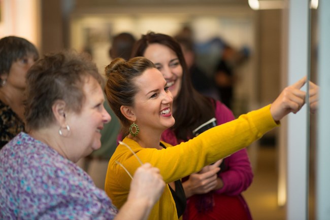 A woman smiles and points to a display case.