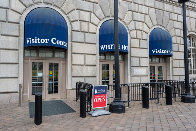 A stone building with three sets of doors with blue awnings.
